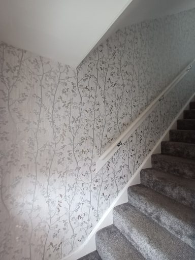 New wallpaper fitted Textured wall with floral wallpaper beside carpeted stairs.